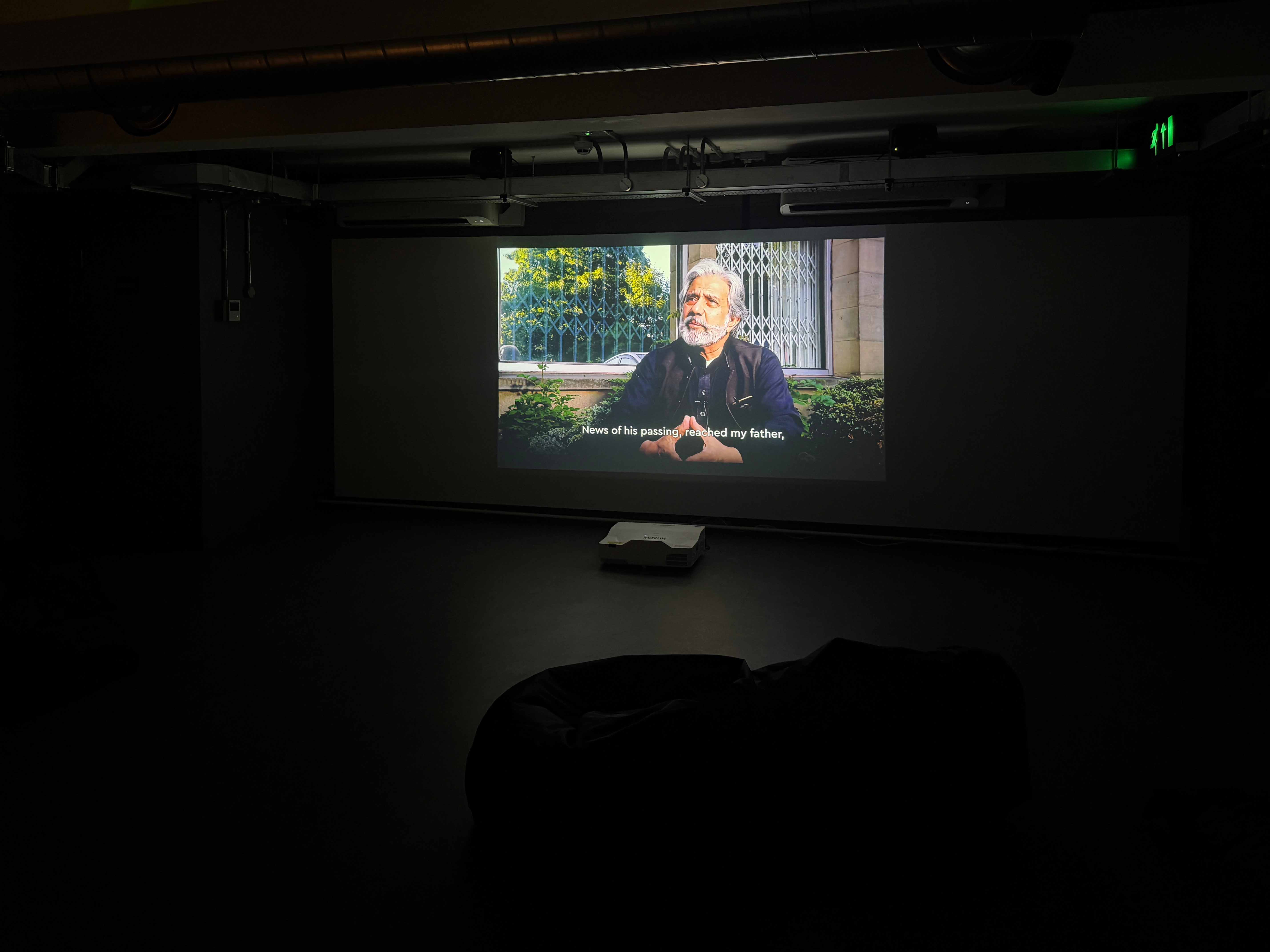 A dark room with a projection of a man sitting down
