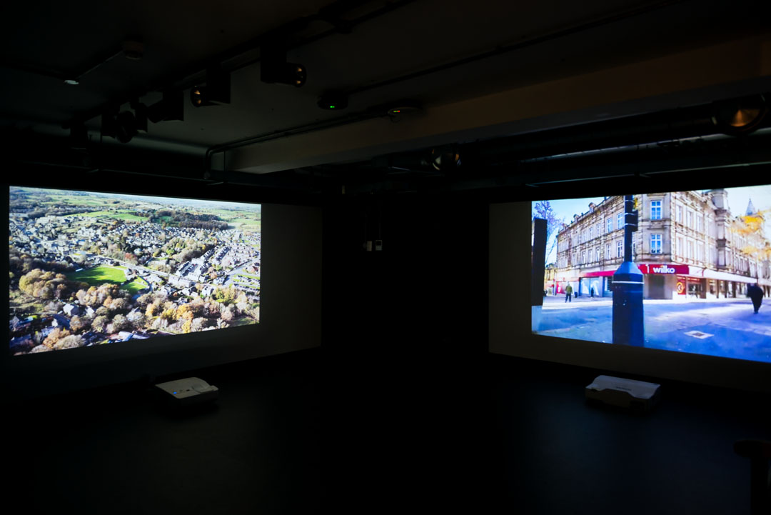 Two projectors on opposite walls showing films of Huddersfield