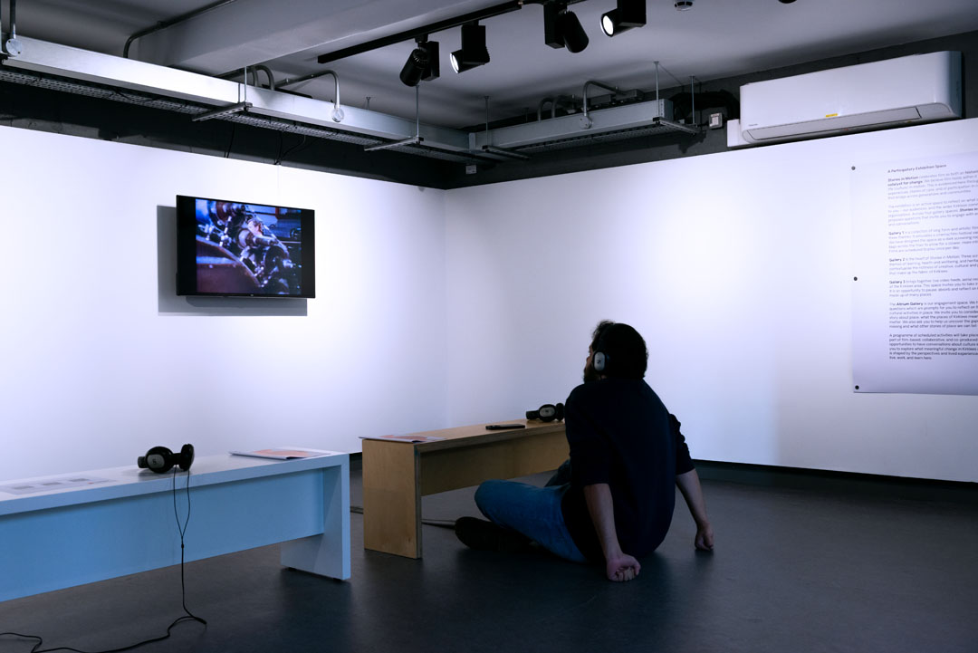 A person sat on the floor with headphones on watching a TV