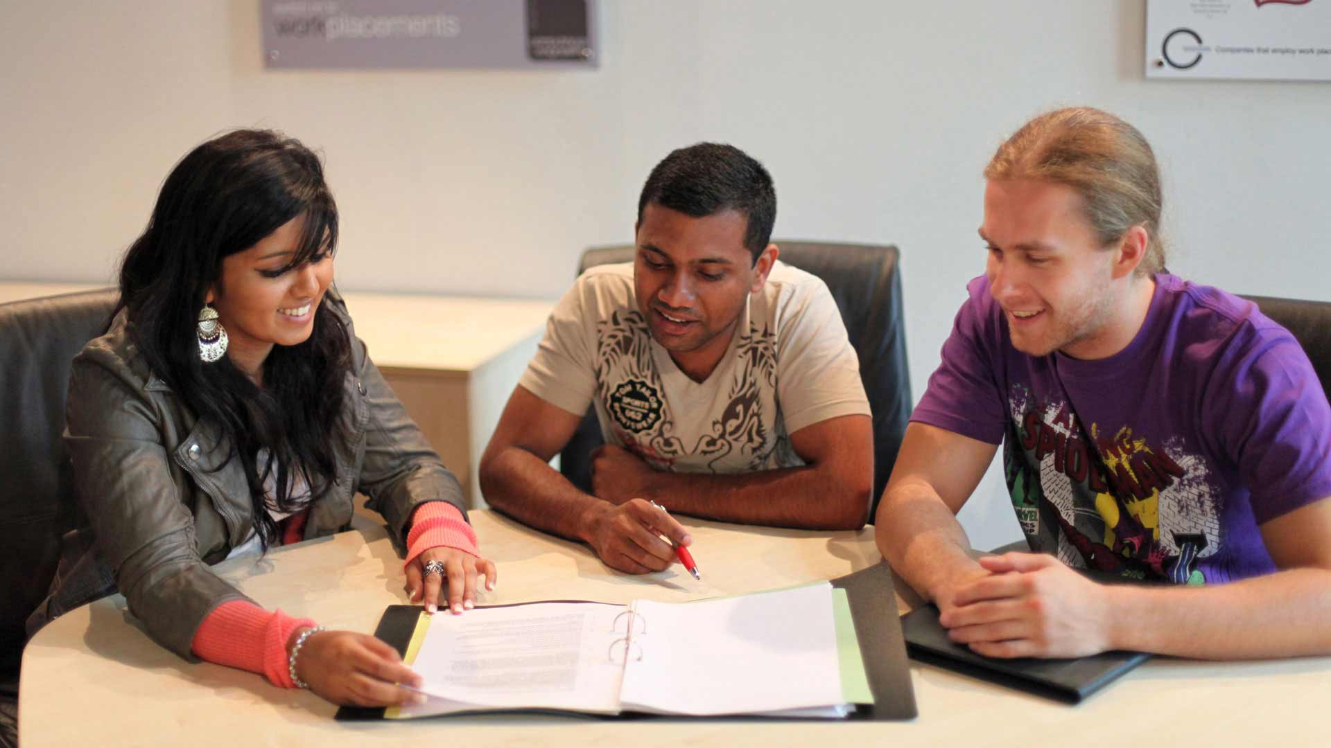 Three students sat reading revision notes